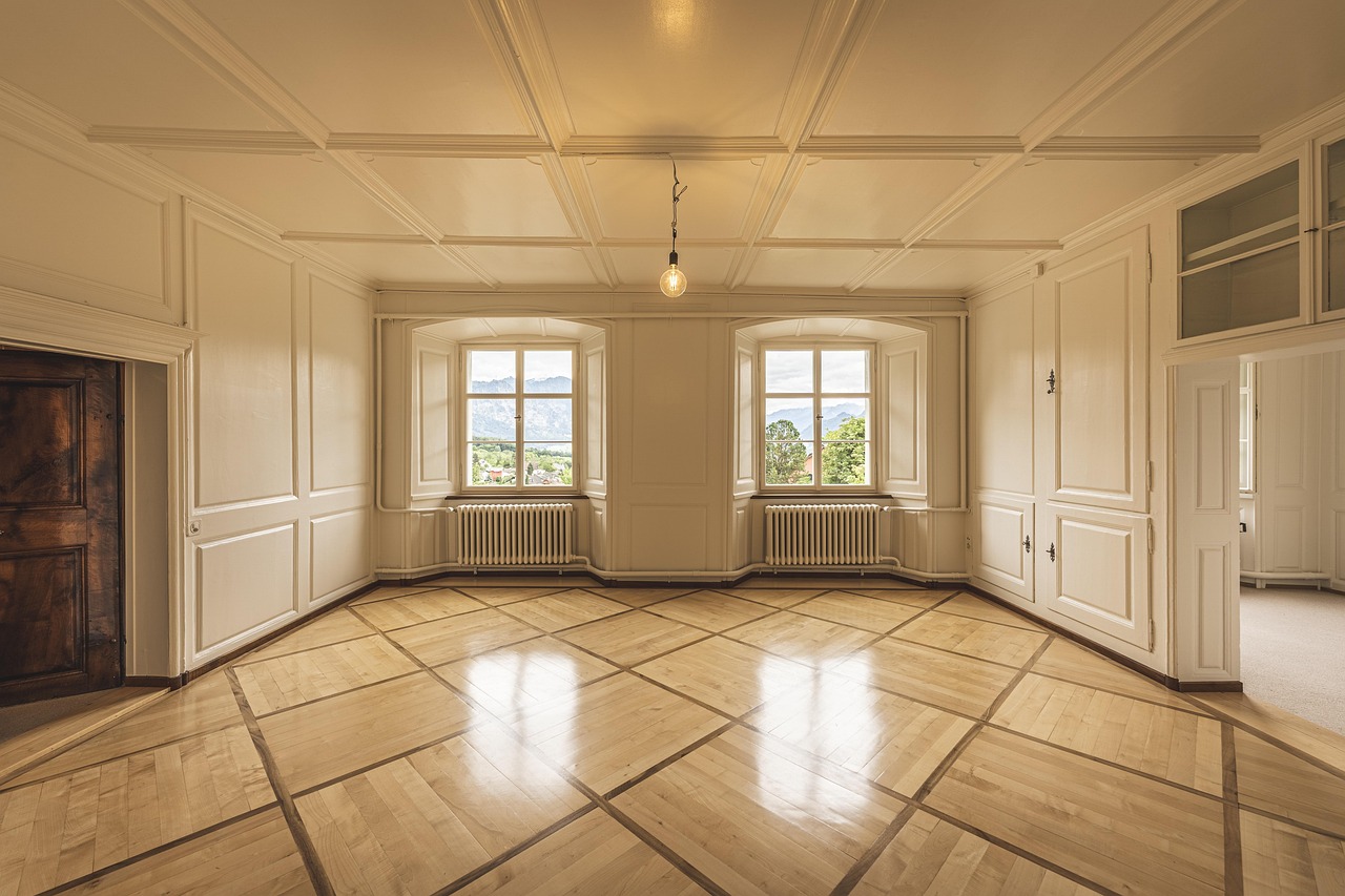A landlord using a smartphone to take a photo of a clean, bright apartment living room during a walkthrough.