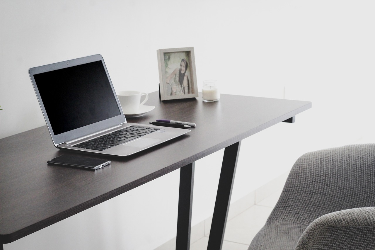 A landlord sitting at a clean wooden desk reviewing a rental lease agreement document with a smartphone nearby.